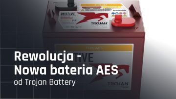 Nowa bateria AES firmy Trojan Battery, przedstawiona z bliska, z widocznymi etykietami i charakterystycznym logo. Tekst "Rewolucja-e Nowa bateria AES od Trojan Battery" wskazuje na innowacyjny produkt w dziedzinie akumulatorów.